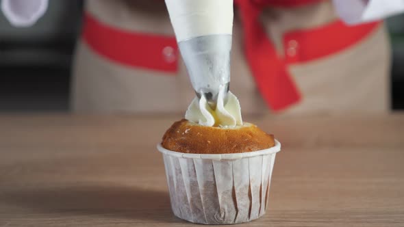 Pastry Chef Decorates Muffin in Paper Cups White Cream with Pastry Bag