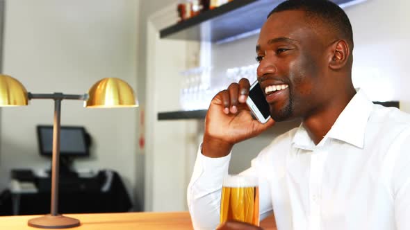 Man talking on mobile phone while having beer at counter