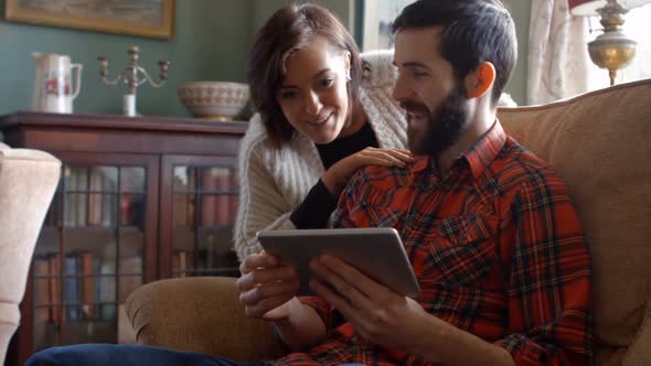 Couple using digital tablet in living room