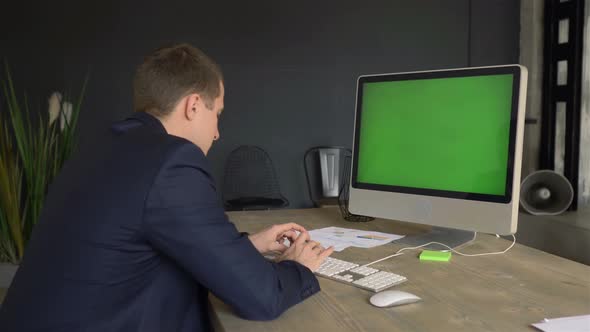 businessman sitting in front of a green screen monitor