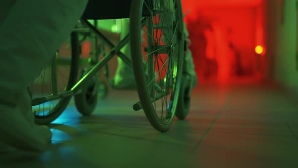 A Paramedic is Driving a Mad Male Patient in Wheelchair Down Corridor in Mental Hospital