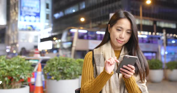 Woman use of cellphone in the city background at night