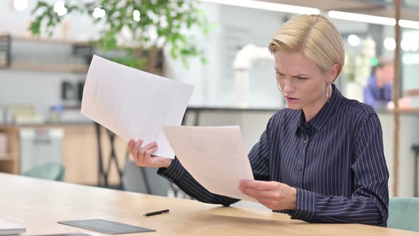 Disappointed Businesswoman Feeling Shocked Reading Documents in Office 