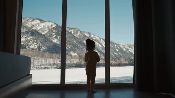 A Small Child Approaches the Window at Home During Self Isolation