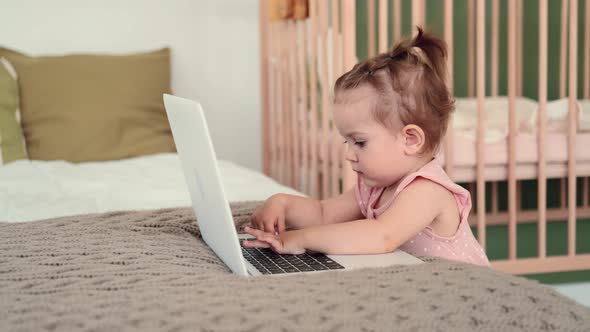 Funny Kid Typing on Laptop at Home on Bed