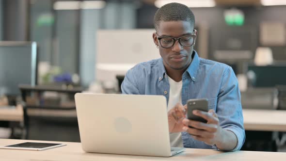 Young African American Man Using Smartphone at Work