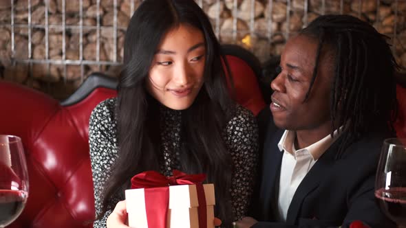 African Man with Corean Woman Unpacking Present at Restaurant