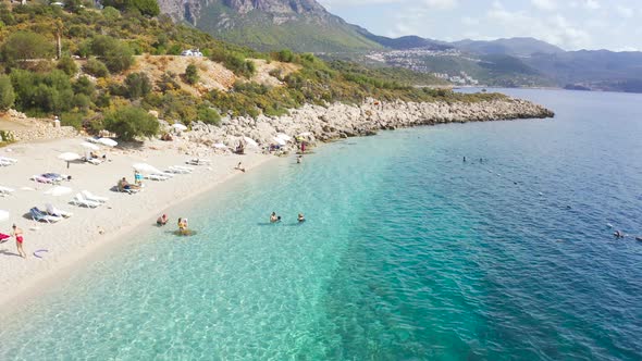 Aerial View Azure Sea and Swiming People on the White Sand Beach on High Mountains Background in Kas