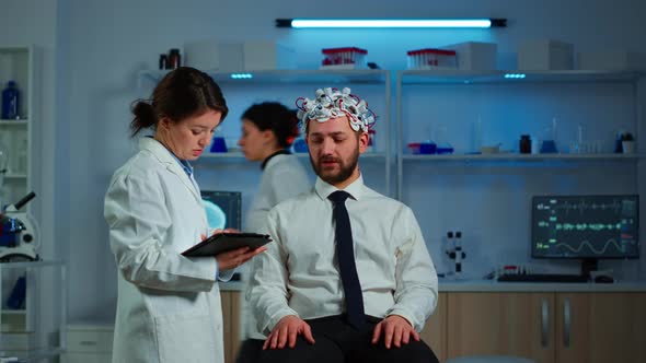 Patient Wearing Brainwave Scanning Headset Discussing with Neurological Researcher