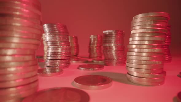 Stacks and Rows of Shiny Coins on White Surface at Red Light