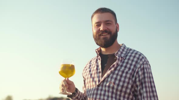 Man with Beard Smiles and Drinks a Cocktail