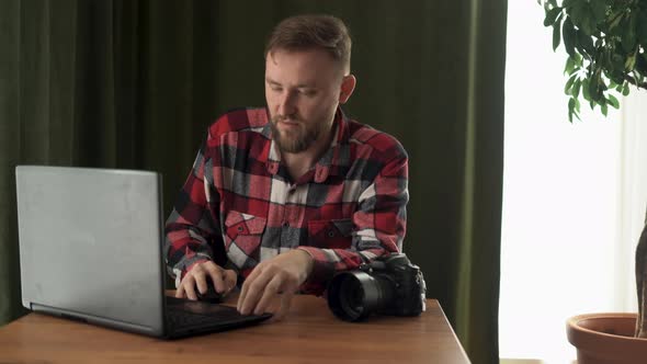 Tired Male Photographer Suffering From Headache at Workplace at Home at Laptop