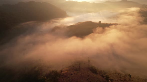 The rays of the sun shine through the clouds into the misty sea above the mountains in the morning