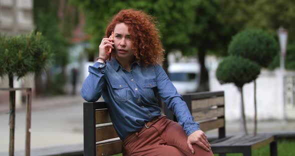 Attractive Young Ginger Woman Talking on the Phone, Surprised Face on City Background