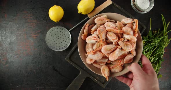 The Men's Hand Puts the Bowl with Shrimp on Cutting Board