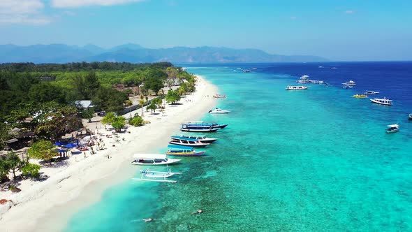 Natural aerial island view of a white sandy paradise beach and aqua blue ocean background in 4K