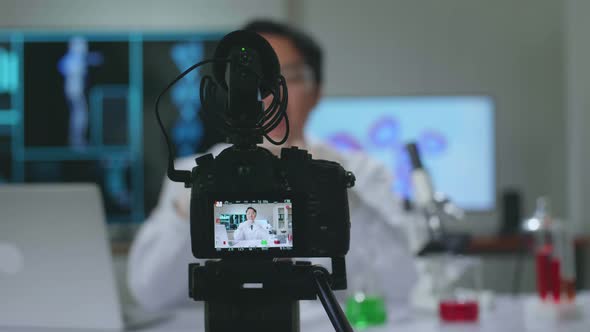 Asian Scientist Researching In The Laboratory With A Microscope And Speaking To The Camera