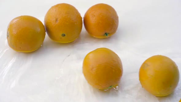 SLOMO of Oranges in Water on White Backdrop