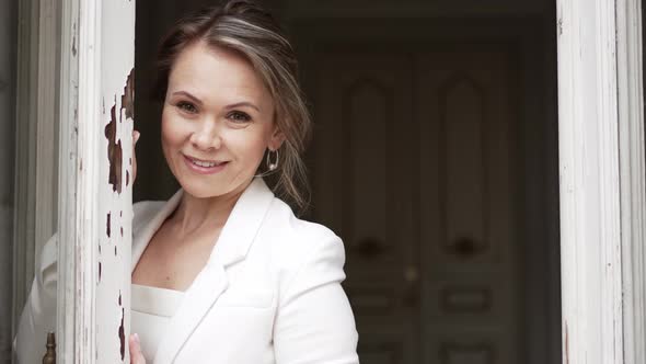 an Attractive Blonde Woman in a White Suit By the Window