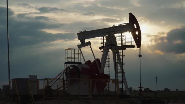 Resource Extraction, an Oil Rig in the Field Pumps Out Oil, View of an Oil Rig at Sunset, Fuel