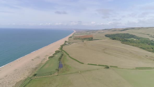 Aerial tracking from right to left above the stunning Chesil beach which stretches west along the co