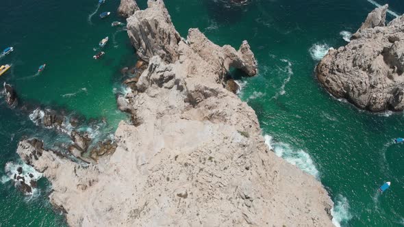 Aerial View of Rock Formations in Ocean with Boats and Coastal Town