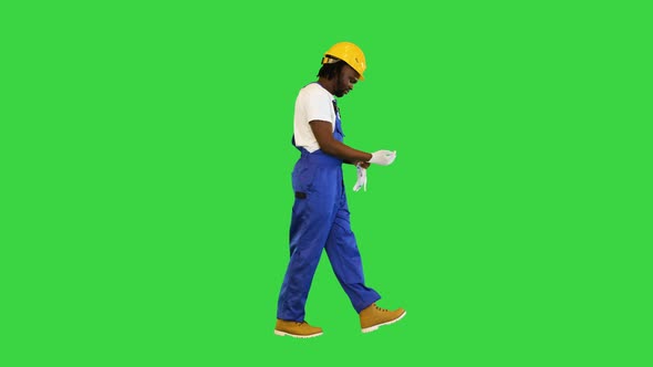 Construction Worker Putting on Gloves While Walking on a Green Screen Chroma Key