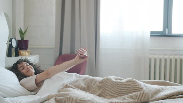 Beautiful Girl Sleeping Then Waking Up and Stretching Indoors in Cozy Bedroom