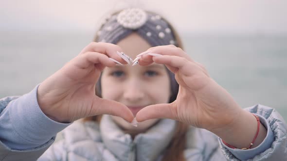 Little Girl Makes a Heart with Her Hands