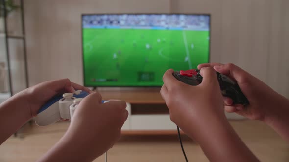 Close Up Children's Hands Holding Joystick Game Play Soccer Video Game On Tv