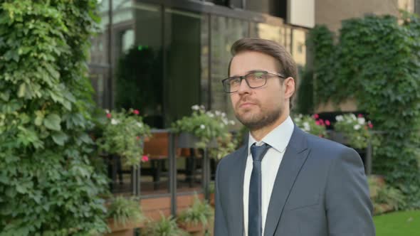 Serious Businessman Walking in Street, Side View