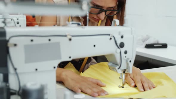 Seamstress Using Sewing Machine at Work in Tailoring Workshop