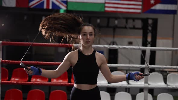 Young Woman in a Black Sports Top with a Skipping Rope in a Boxing Gym in the Ring