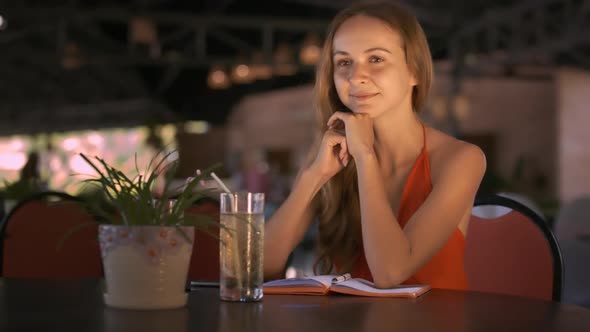 Girl Sits at Table Smiles Listening To Friend Story