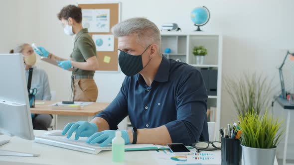 Woman Taking Temperature of Business People Working in Office During Corona Virus Outbreak alt