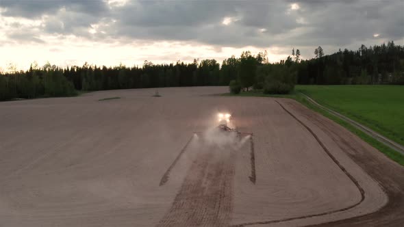 AERIAL - Tractor sowing seeds at dusk, Hedemora, Sweden, wide shot forward