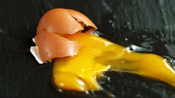 Super Slow Motion Shot of Falling and Breaking Whole Egg on Black Table at 1000 Fps.