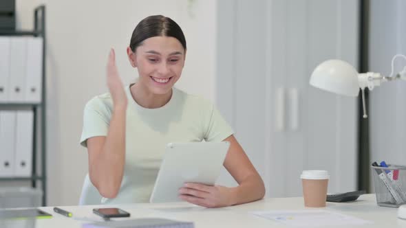 Young Latin Woman Celebrating Success on Tablet 