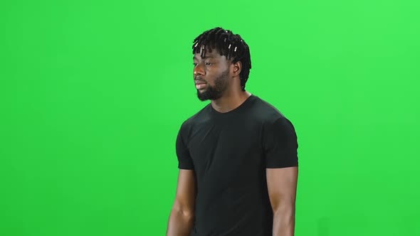 Portrait of African American Man with Dreadlocks Is Walking at Green Screen, Chroma Key