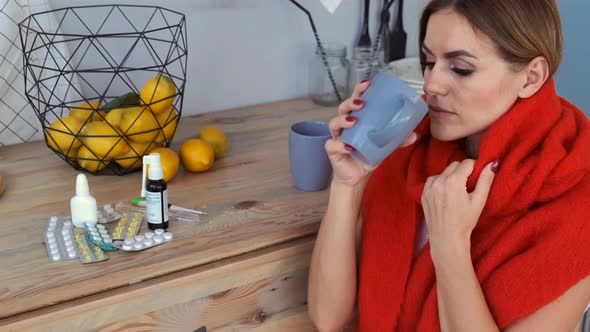 Sick Woman Drinking Tea and Taking Medicine at Home