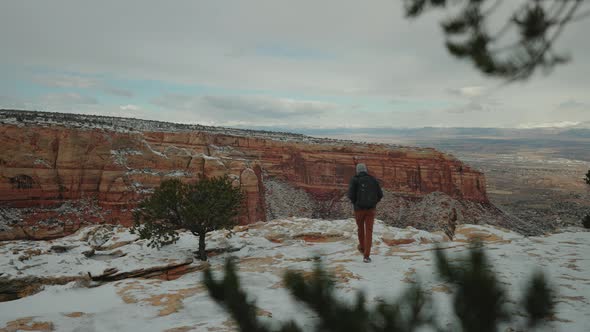 Male Walking on the edge of a snowy canyon in a storm. Adventurer battling the elements.