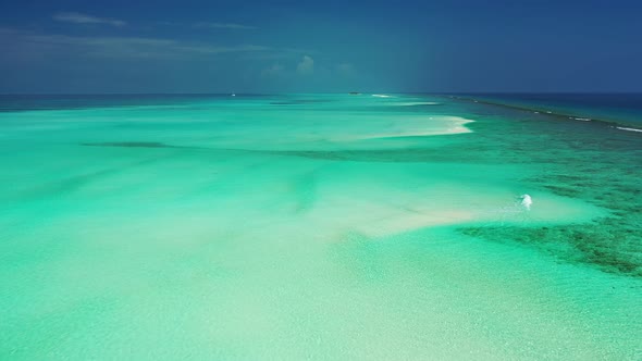 Wide angle overhead tourism shot of a white sandy paradise beach and turquoise sea background in col