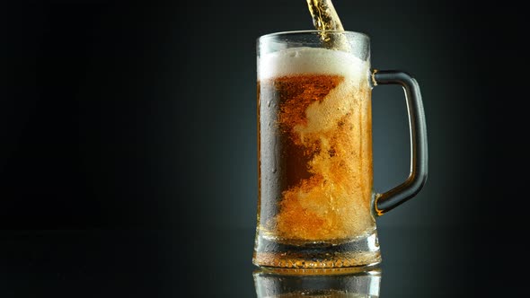 Super Slow Motion Shot of Pouring Fresh Beer Into Glass on Black Background at 1000Fps alt