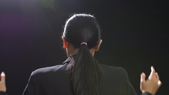 Back View Of Asian Speaker Woman In Business Suit Speaking In The Black Screen Studio