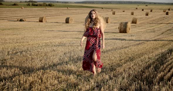 The Girl Walks Across The Field Among The Collected Sheaves Of Hay