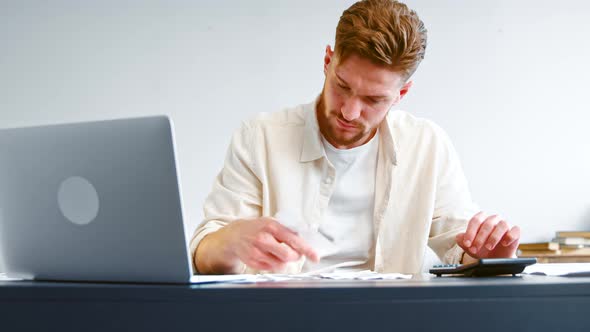 Skilled accountant looks at paper checks and summarizes total on calculator