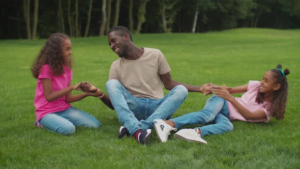 African Dad with Girls Enjoying Leisure Outdoors