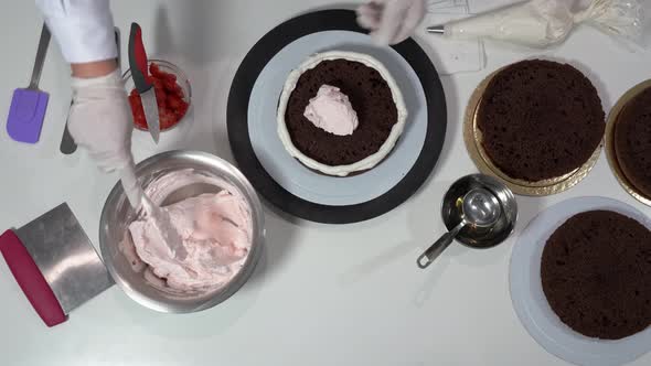 Front Shot of a Baker Using an Icing Spatula to Carefully Touch Up Sides of Cream Covered Cake