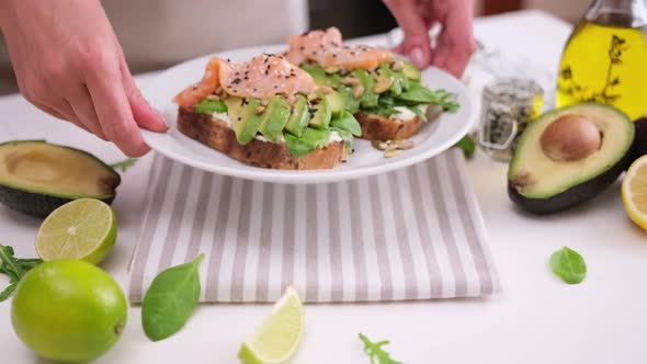 Healthy Breakfast or Snack Woman Puts Plate with Soft Cheese Avocado and Salmon Sandwiches on a