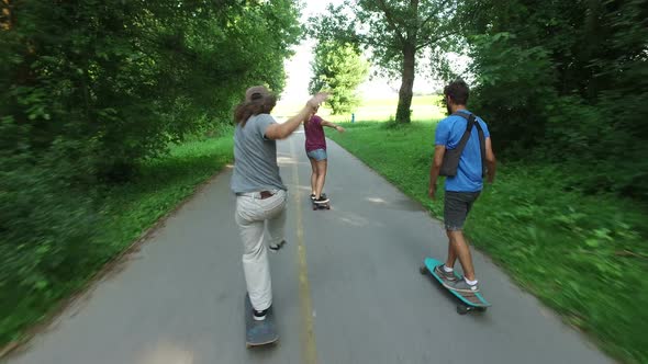 Back view of cool friends having fun riding on a skateboard